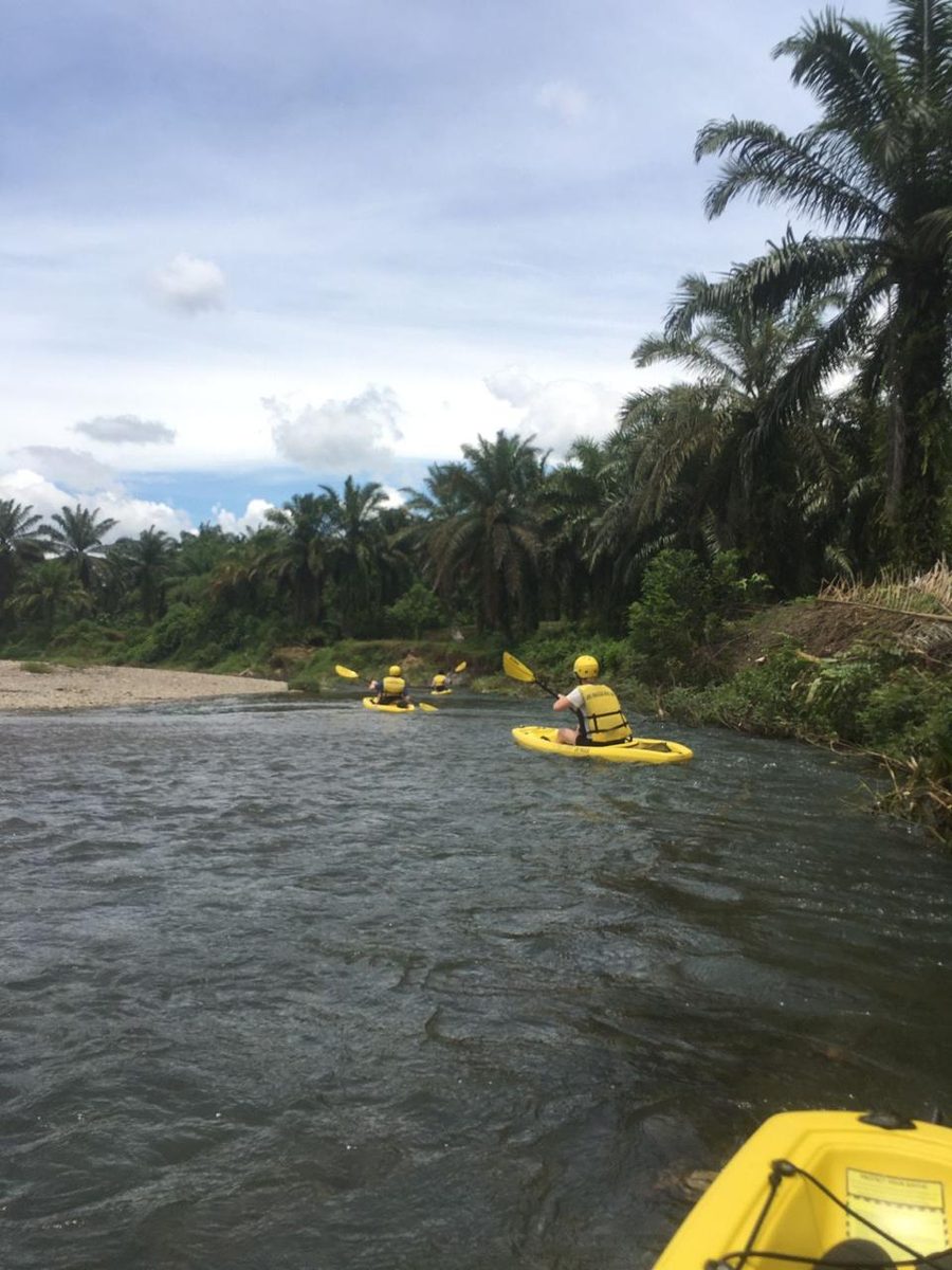 A yellow Jungle Kayak boat resting in a quiet bend of the Landak River, surrounded by jungle and giant boulders